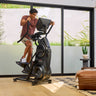 A man riding a BowFlex Max Total 16 in a modern living room.