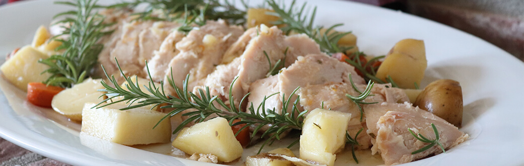 Sliced turkey, potatoes, and carrots on a plate with rosemary sprigs.