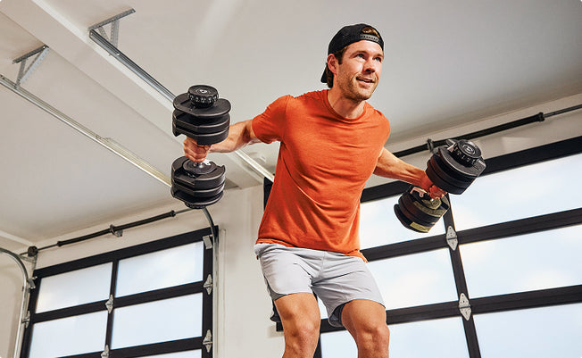Man exercising with Results Series 52 SelectTech Dumbbells in a modern garage.