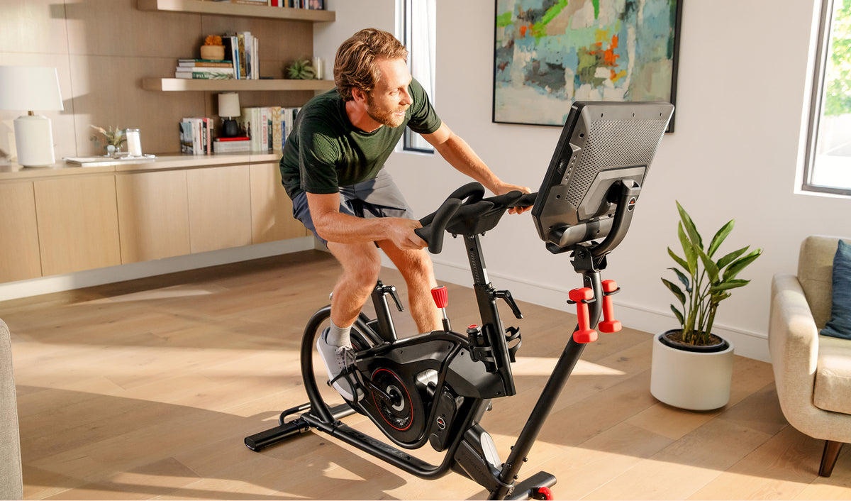 Man riding the BowFlex VeloCore Bike 22 in leaning mode in a home setting.