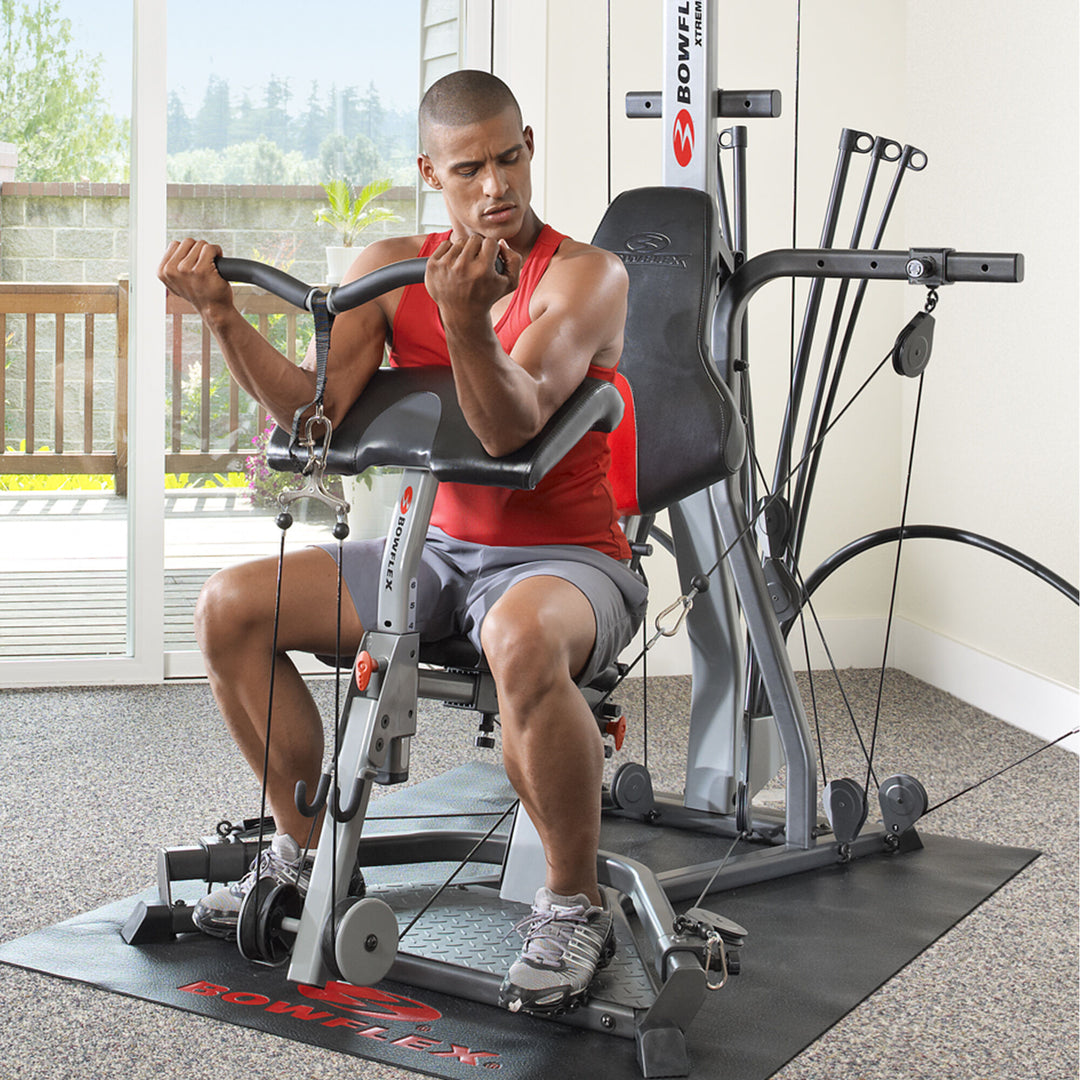 Man using the BowFlex Preacher Curl Attachment on an Xtreme 2 SE Home Gym in a home.