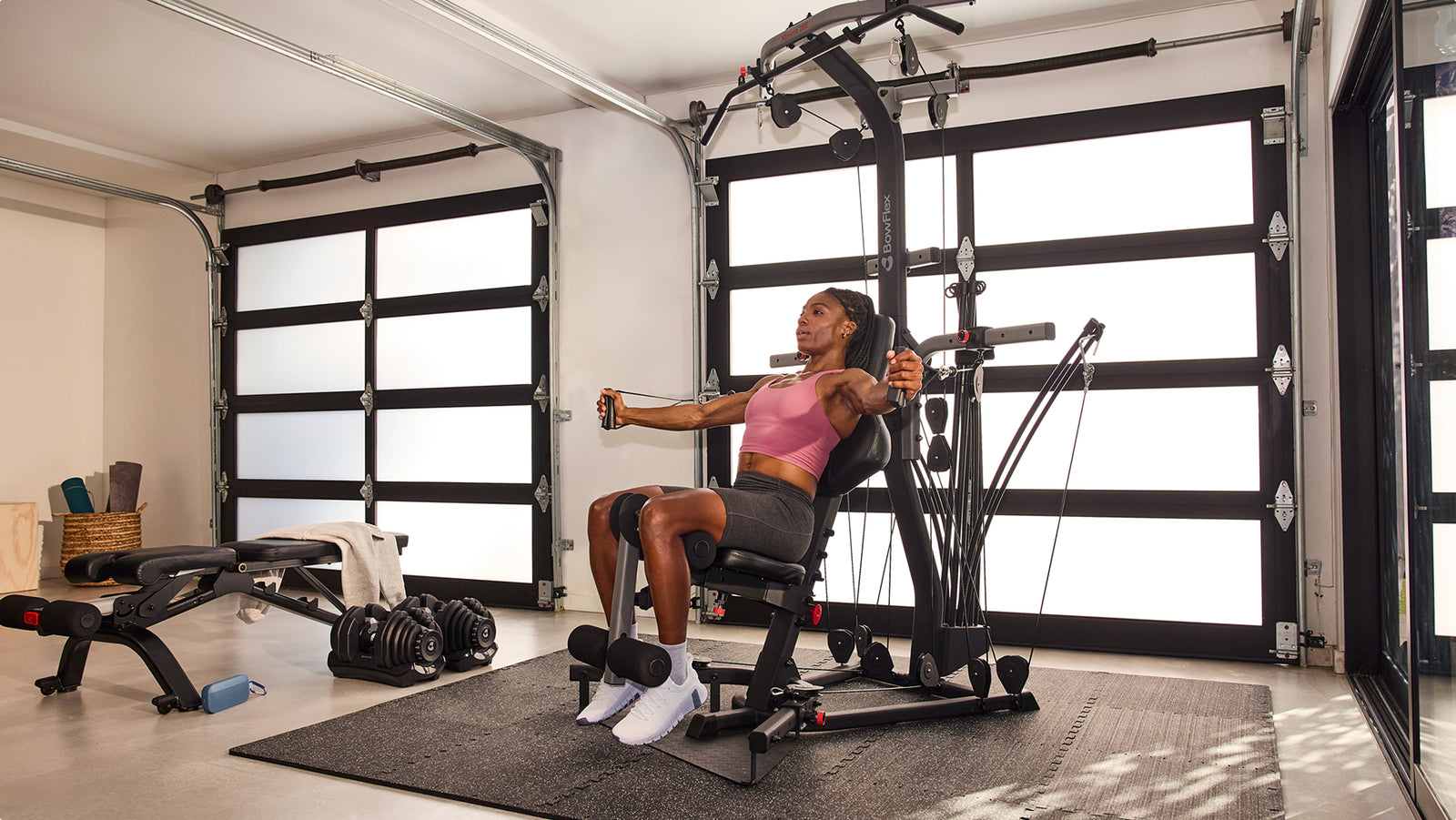 Woman using the cable pulley system during a seated workout on the BowFlex Xtreme 2 SE in a home gym.