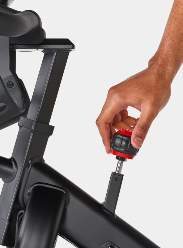 A person's hand on the BowFlex C6 Bike resistance level adjustment knob.
