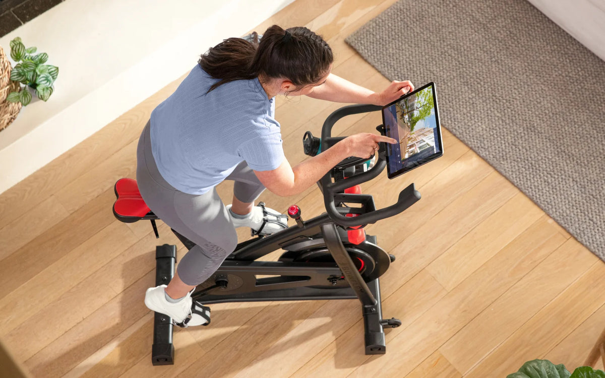 Woman using a BowFlex C6 Bike with the JRNY fitness app