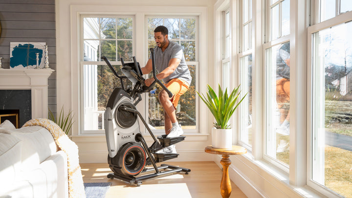 Man working out on BowFlex Max Trainer M6 in a home setting.