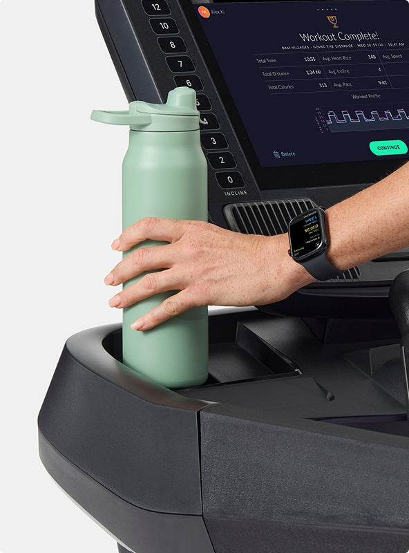 Hand placing water bottle in the BowFlex T16 Treadmill cup holder.