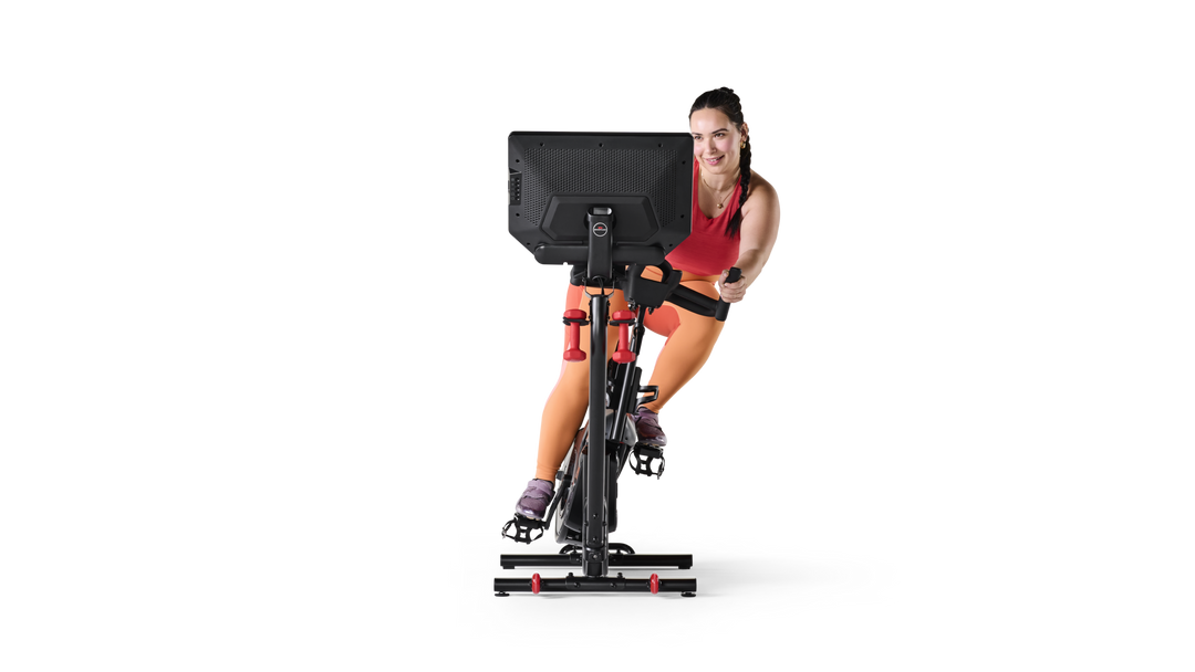 Woman exercising on a stationary bike with a screen in front of her on a white background