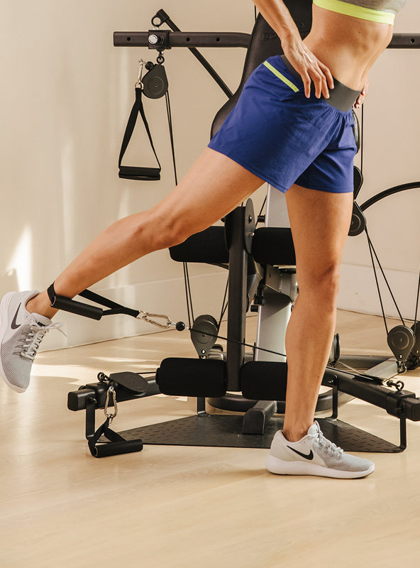 Person doing a leg exercise using a BowFlex Xtreme 2 SE dual purpose grip around ankle.