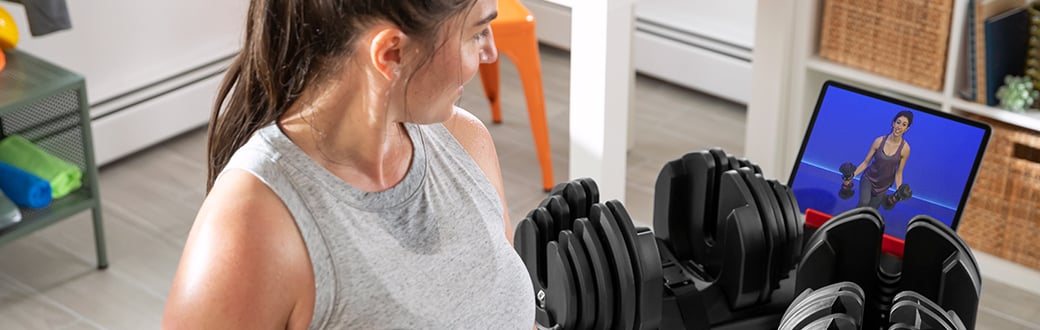 Woman a SelectTech dumbbell strength workout in a living room