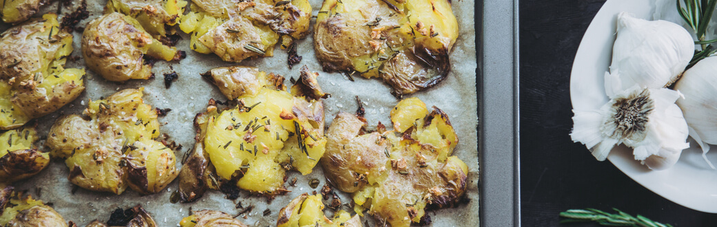 Cooked garlic rosemary smashed potatoes on parchment paper.