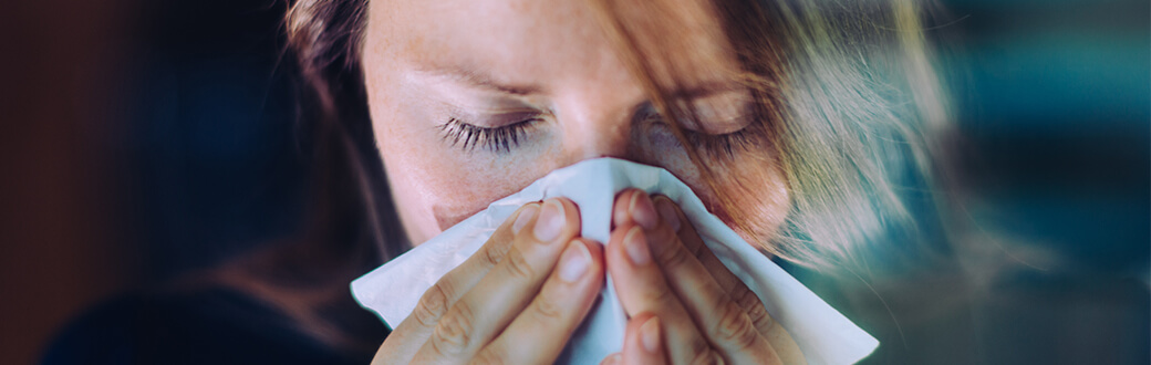 A person sneezing into a tissue.