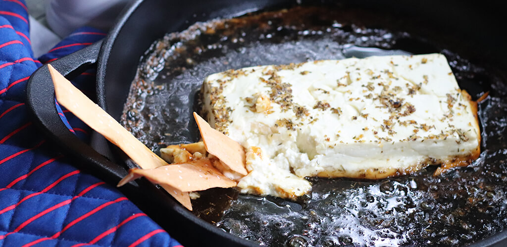 Baked feta, herbs de provence, and agave in a pan.
