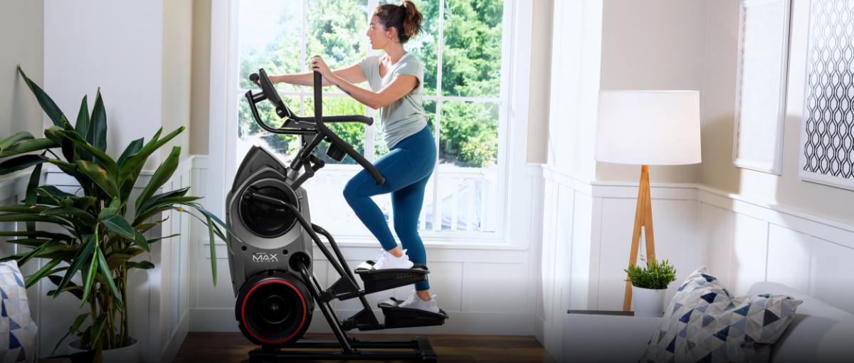 A woman using a Max Trainer compact elliptical located in her home's landing.