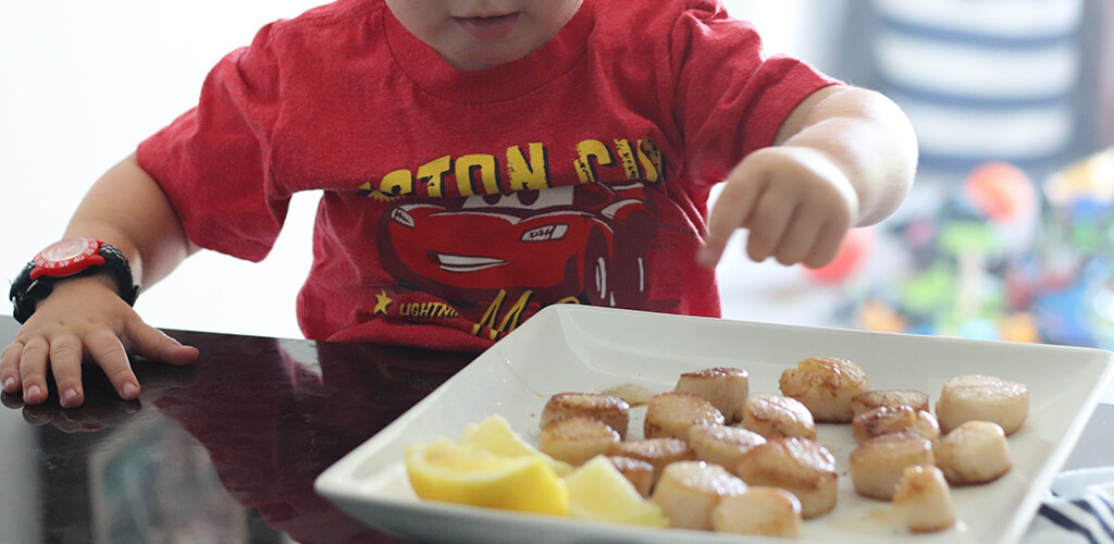 a child eating seared scallops