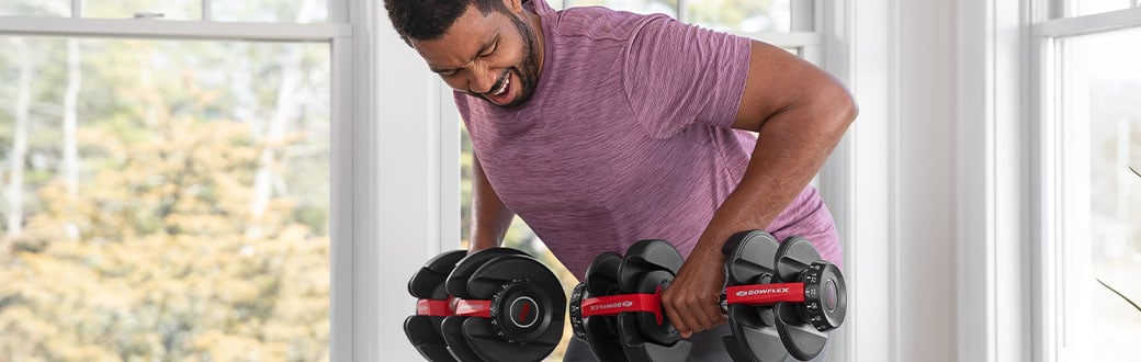 A man performing bent over rows with adjustable dumbbells.