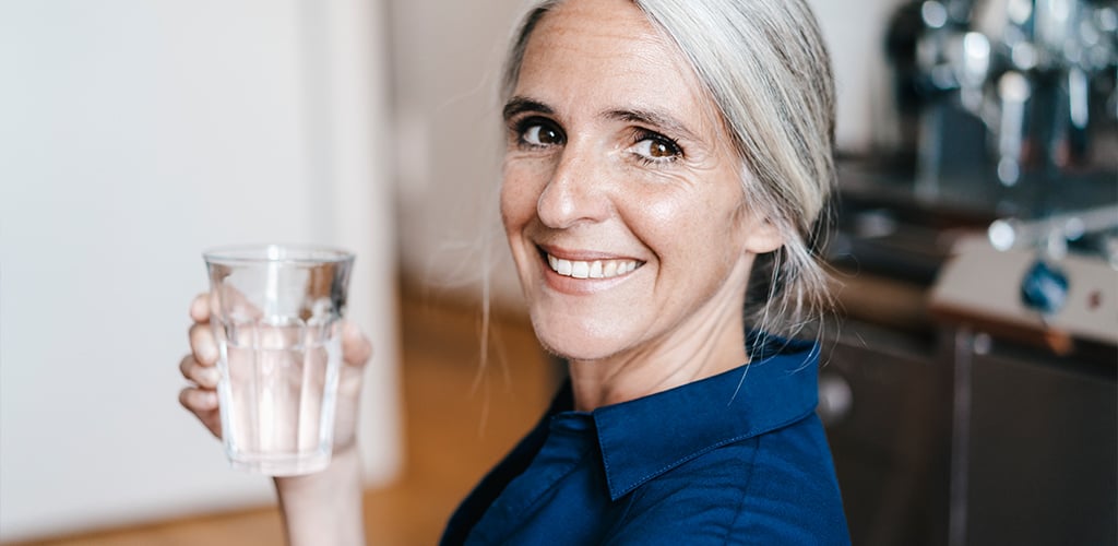 A woman holding a glass of water.