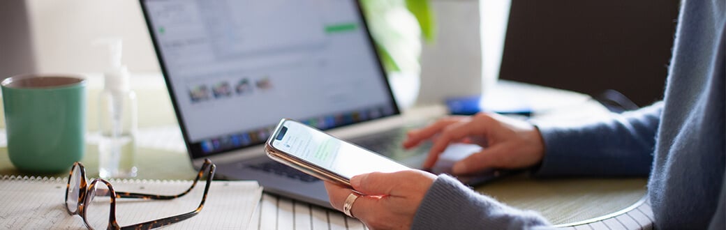 A person using a computer and smart phone.