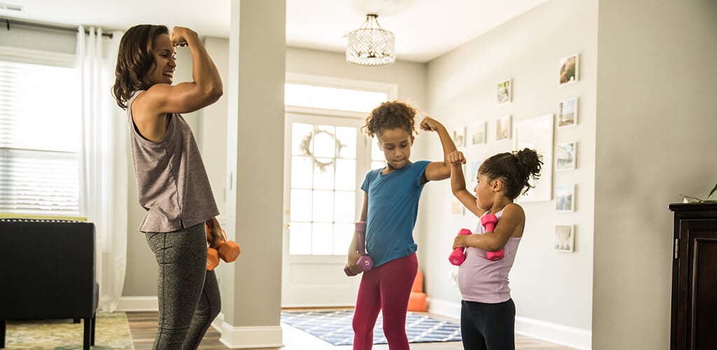 A woman and two children flexing their biceps.