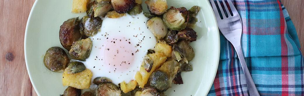 Pumpkin and Brussels sprouts topped with an egg on a plate.