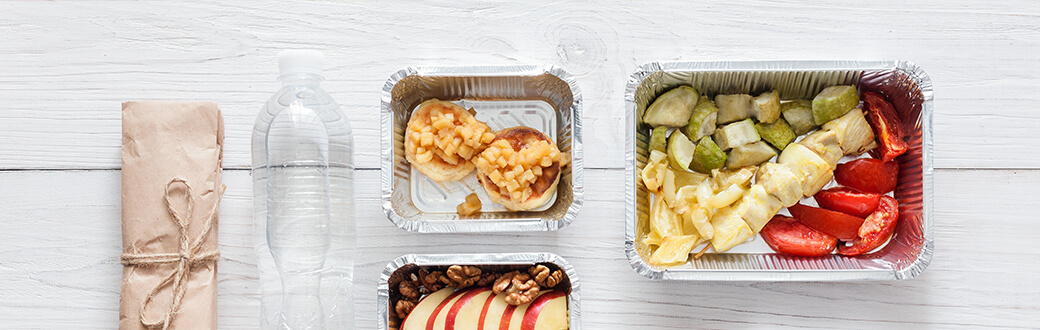 Camping dinner ideas in foil containers on a table.