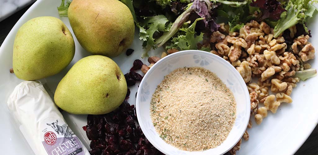 fresh ingredients for goat cheese salad, including pears, cranberries, and walnuts