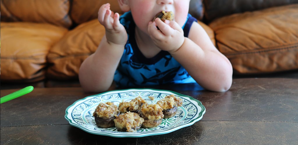 a toddler eating stuffed mushrooms