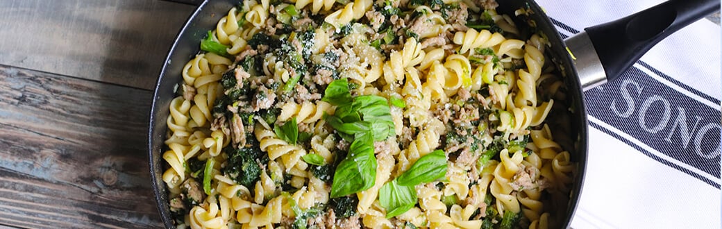 Kale and sausage pasta in a skillet.