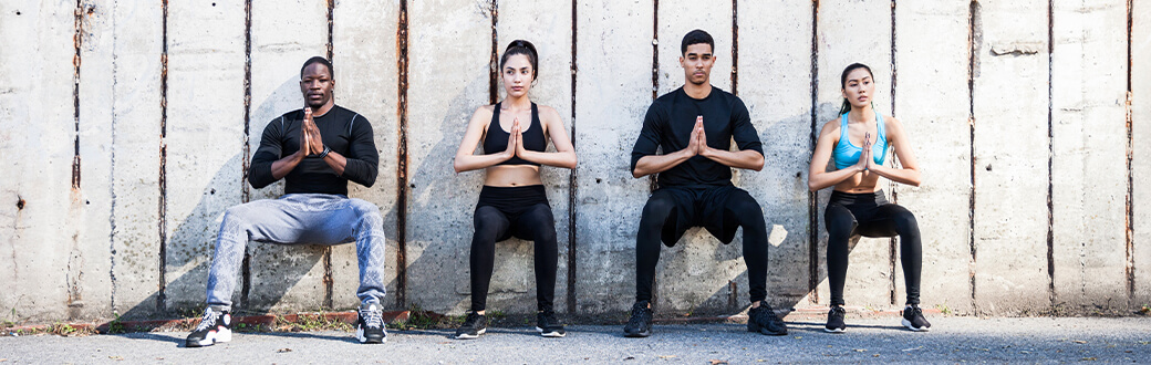 Four people performing wall sits.