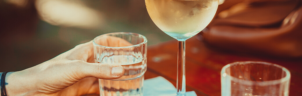 A glass of white wine and a glass of water.