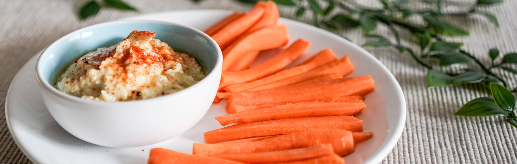 carrot sticks and hummus on a plate.