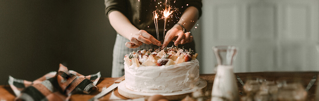 A woman in front of a birthday cake.