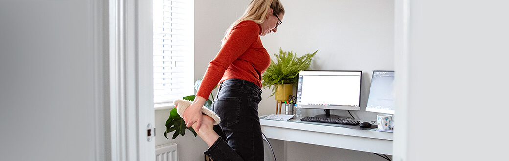 A woman stretching in her home office.