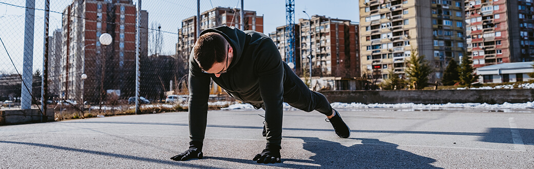 A man performing a plank outside during winter.