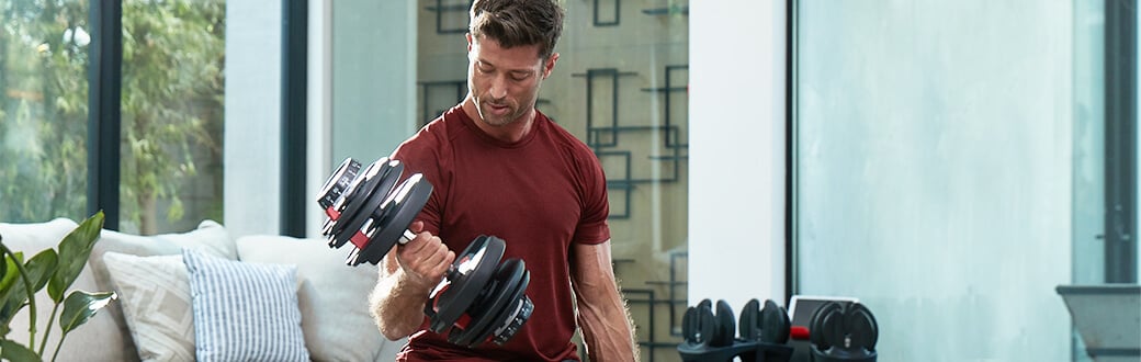 A fit man using BowFlex SelectTech Dumbbells.