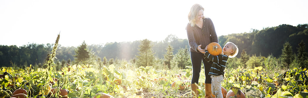 A woman with her child carrying a pumpkin