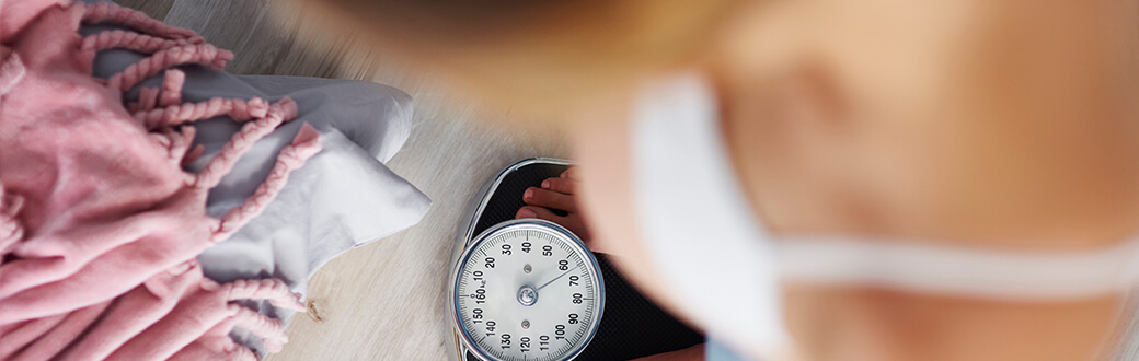 A woman standing on a scale weighting herself.