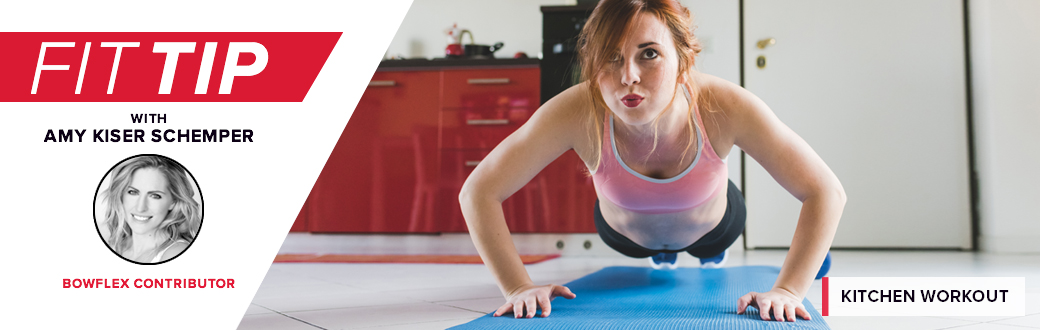 A woman performing a push-up in a kitchen.