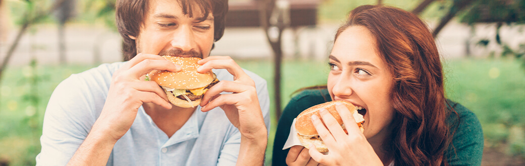 A woman and a man eating burgers.