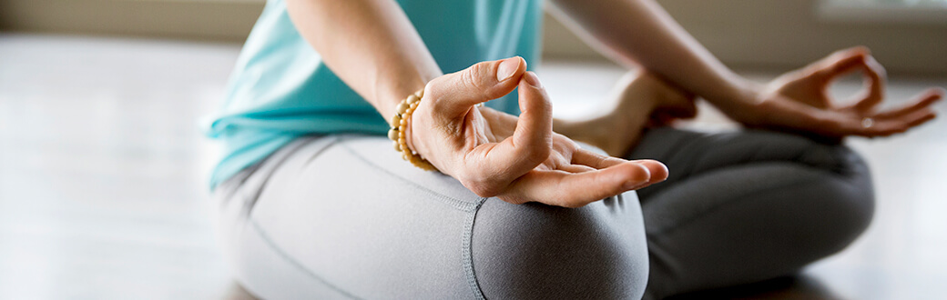 A woman sitting crossed-legged, meditating.