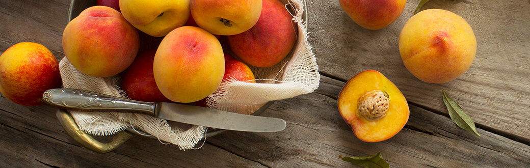 Peaches on a table being prepared for National Peach Month - Peach Crisp Recipe.