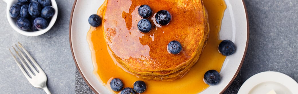 pancakes with fresh blueberries on a plate.