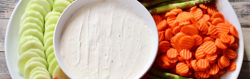 Cut veggies next to a bowl of white truffle dip.