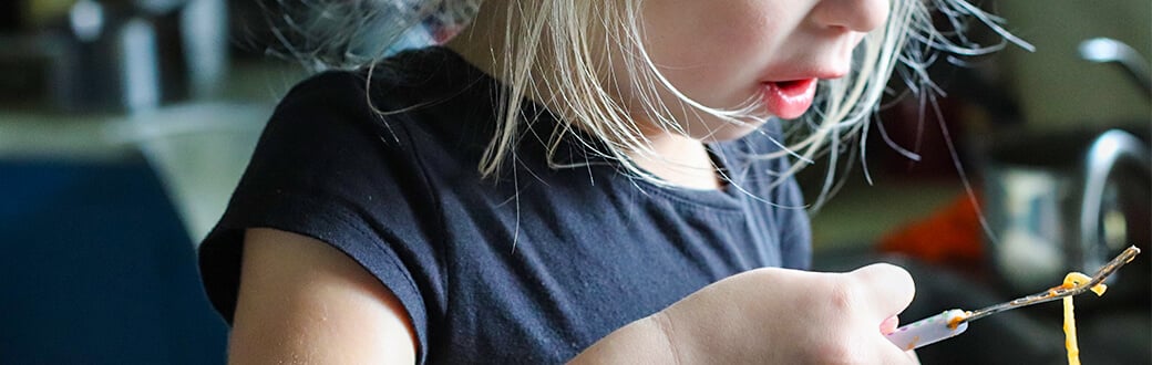 Young child eating spaghetti with a fork