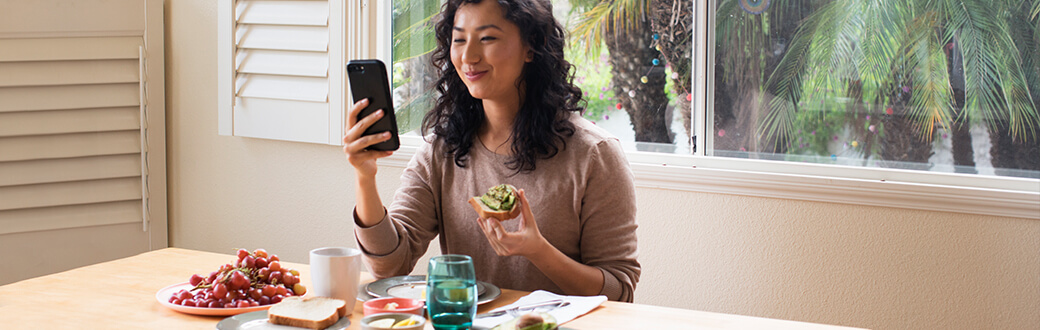 A woman using her phone while eating.