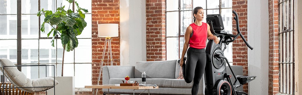 A woman stretching next to a BowFlex Max Total