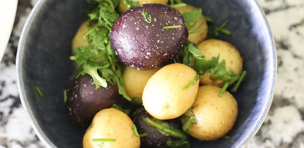 Lemon, arugula, and herb potatoes in a serving dish.