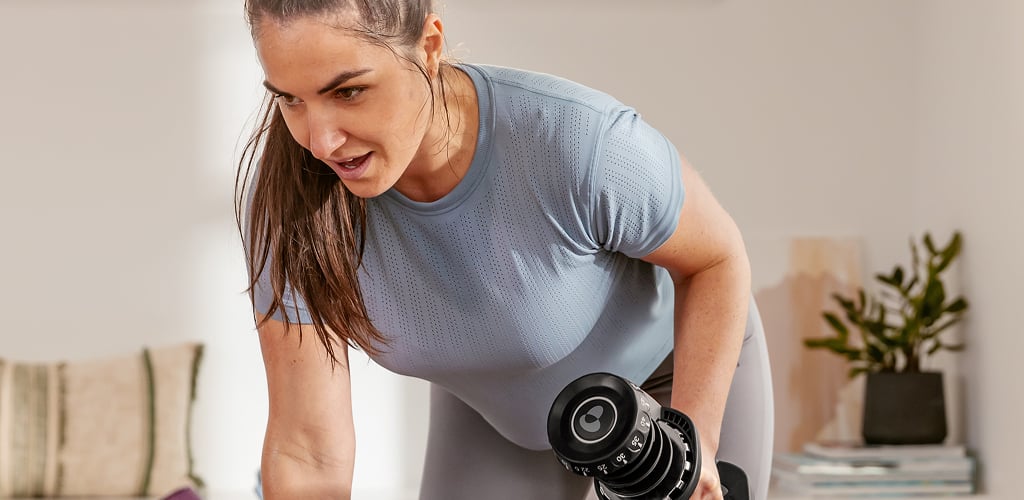 Woman using bowflex dumbbell