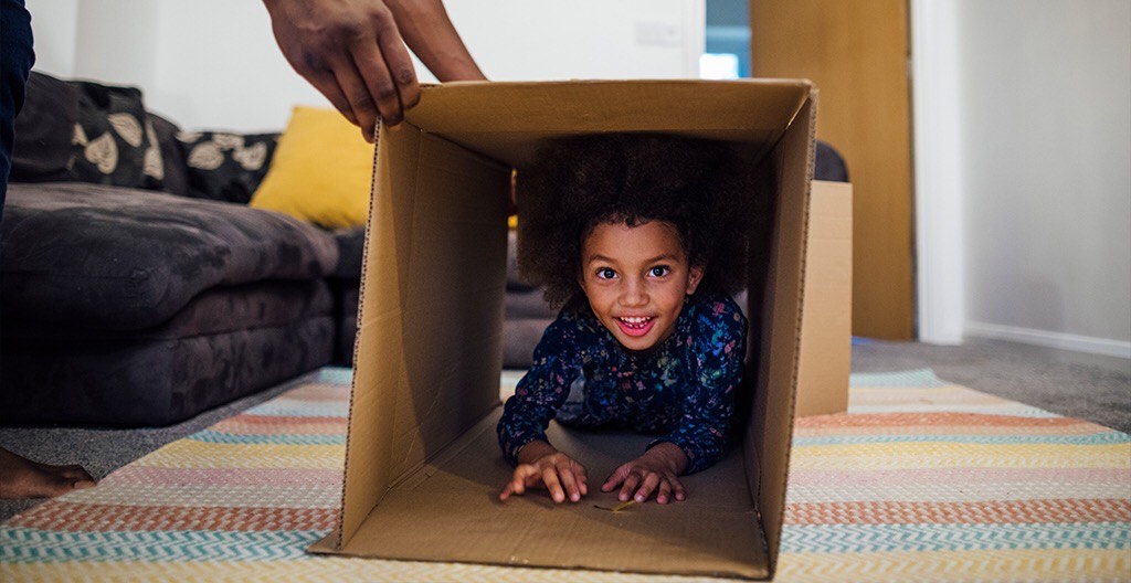 Child climbing through a cardboard box