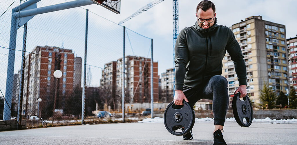 A man performing a weighted lunge outside during winter.