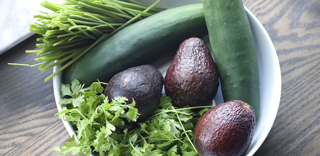 avocados, cucumbers, chives and cilantro in a bowl